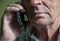 Close-up face of Caucasian elderly man talking on the phone. Parts of a man`s face with deep wrinkles, selective focus, shallow