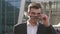 Close-up face of confident handsome smiling businessman adjusting glasses and staring at the camera. Outdoor airport