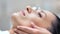 Close-up face of confident pretty woman during microdermabrasion beauty procedure using equipment