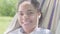 Close-up face of cute happy African American woman lying in the hammock, relaxing in the garden. Leisure outdoors