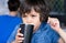 Close up face Cute toddler boy drinking cold drink, Happy Child sitting in cafe drinking soda or soft drink from paper cup,