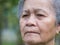 Close-up of face elderly woman with short white hair, feeling worry and standing in garden. Asian senior woman unhealthy and make