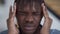 Close-up face of exhausted man rubbing temples having migraine symptoms. Headshot portrait of African American