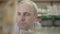 Close-up face of focused confident man looking at canned food on shelf. Portrait of focused Caucasian buyer choosing