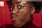 Close-up face of funny dark skinned young girl crushed on glass  on dark red studio background.