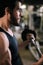 Close-up of face of handsome bearded young man with muscular wiry body working out with barbell.