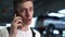 Close-up face of handsome cheerful mechanic male talking on mobile phone standing in auto repair shop garage with