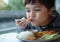 Close up face healhty boy eating chicken katsu with steam rice and mixed vegetables salad, Mixed race child enjoy meal in