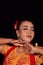 Close-up face of an Indonesian woman with makeup and an orange dress while wearing a piece of gold jewelry on her neck