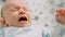 Close-up face of infant crying. Caucasian baby yelling. Child crying.  Little newborn in a bad mood