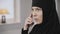 Close-up face of muslim woman with brown eyes talking on smartphone. Irritated lady in black hijab quarrelling with