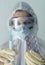 Close-up of the face of a nurse dressed in protective coveralls, mask and glasses offers medication, syringe and pills