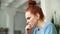 Close-up of face of overstressed worried young redhead woman working on laptop.