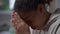 Close-up face of overwhelmed young African American woman sitting indoors at home. Side view portrait of worried anxious