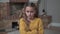 Close-up face of a sad Caucasian girl in mustard sweater crossing hands on chest and shaking her head. Upset child