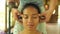 Close up face shotof young gorgeous and relaxed Asian Indonesian woman receiving traditional facial Thai massage with male hands