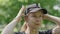 Close-up face of smiling mid-adult sportswoman putting on black cap outdoors. Portrait of happy sportive Caucasian woman