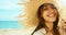 Close-up face smiling woman wearing straw hat at beach in sunshine sunrise on seashore.