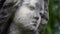 A close up of the face of a statue of a Victorian graveyard angel. With a shallow depth of field and blurred background