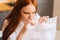 Close-up face of stressed nervous young woman playing pops bubble wrap to calm herself sitting at table in kitchen.