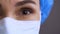 Close-up of the face of surprised female doctor. Shocked Covid-19 surgeon nods head in mask. Macro shoot of a female
