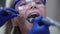 Close-up face teenage girl with open mouth and doctor hands using mouth mirror and dental drill examining teeth in slow