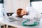 Close-up face of tired exhausted overworked young female doctor in white coat sleeping lying at desk with laptop and