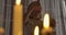 Close-up face of weird Caucasian girl holding doll and candle and looking up. Strange child standing in candlelight in