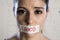 Close up face of young beautiful sad latin woman with mouth sealed on stick tape with the text no food