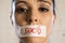 Close up face of young beautiful sad latin woman with mouth sealed on stick tape with the text no food