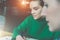 Close-up face of young business women sitting at table and working.Blurred foreground.Girl taking notes in notebook.