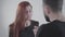 Close-up face of young irritated redhead woman arguing with unrecognizable husband or boyfriend. Two people quarreling