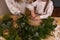 Close-up of faceless young mother with little daughter together making Christmas wreath from spruce