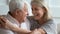 Close up faces elderly wife and senior husband embracing indoors