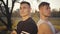 Close-up faces of two young Caucasian bodybuilders standing in sunlight and looking at camera. Handsome strong sportsmen