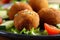 Close-up of falafel balls stuffed with melted feta cheese and served with a refreshing cucumber and tomato salad