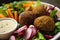 Close-up of falafel plate with assorted pickled vegetables, crispy falafel balls, and drizzled with tahini sauce