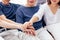 Close up of family with adult children and senior parents putting hands together sitting on sofa at home together. Family unity