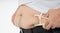 Close up of fat man hands measuring overweight belly by using body fat caliper