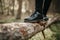 Close up of feet in black shoes walking and balancing on a fallen tree trunk