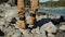 Close up of feet boots climber male hiker traveler man walking and jumping on rocks near mountain river