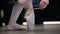 Close-up feet of caucasian female ballet dancer tying pointe shoes. Graceful woman\'s hands tying up laces on pointes