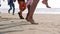 Close-up feet group of lots people walking on the beach and jumping together