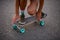 Close-up of feet and knee of girl who stands with skateboard on asphalt