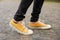 Close up Feet of man while walking commuting to work. Male in yellow sneakers being walking down the street.