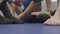 Close up of feet of the men sitting on the floor in the gym resting after training. Pair of black boxing gloves lying in