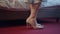 Close-up feet of young Caucasian woman putting on beige luxurious high-heels indoors. Unrecognizable stylish lady in