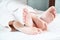 Close-up of the feet of a young couple sticking out from under the covers in the bedroom. Bare feet caress each other