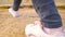 A close-up of the feet of a young girl in white sneakers and gray jeans, who walks over the embossed rocky brown surface