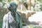 Close up of a female bronze statue of a woman with short hair with cross and cardigan in a park, Germany